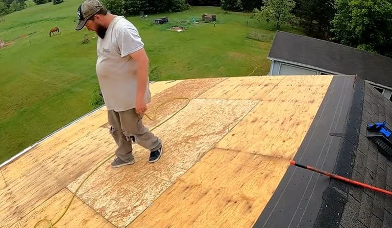 Roofer walking across new plywood roof decking after the old roofing was removed