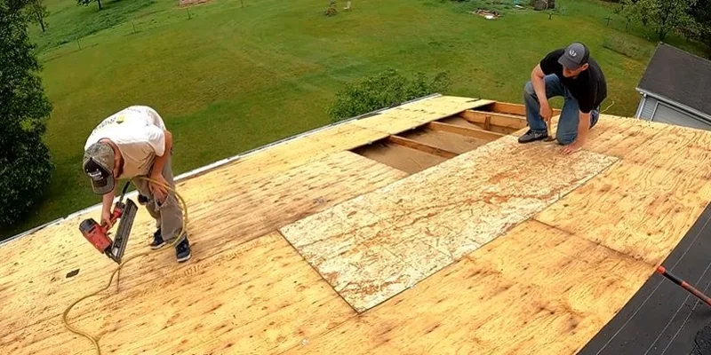Roofers replacing damaged sections of plywood roof decking during a tear-off
