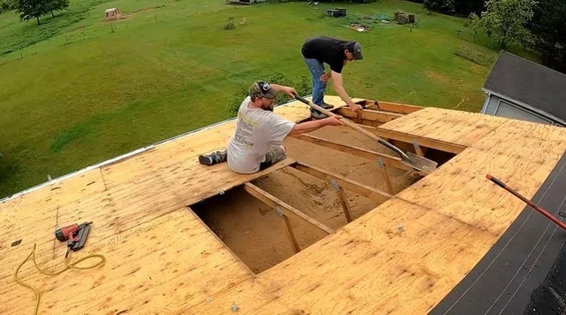 Roofers cutting out damaged sections of plywood roof decking