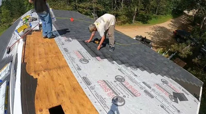 Roofers laying underlayment over bare roof decking during a roof replacement
